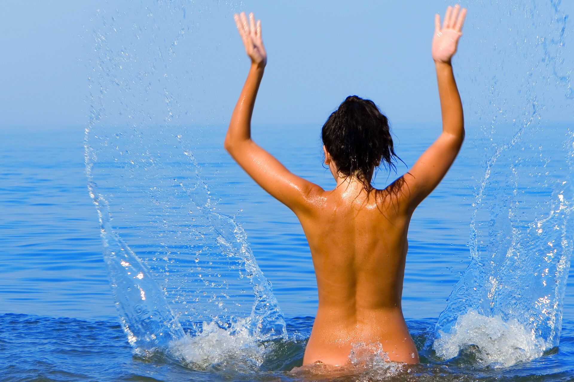Pretty young woman on the sea? Topless young woman covering her breasts by hands