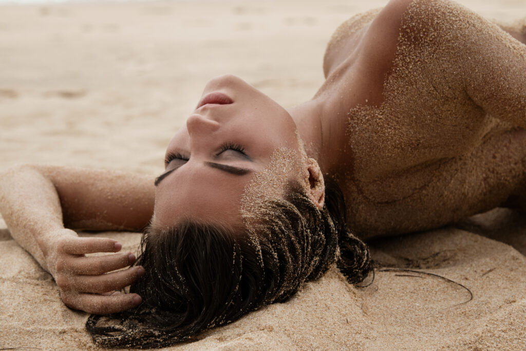 Gorgeous young woman lying in the sand, her body artfully covere