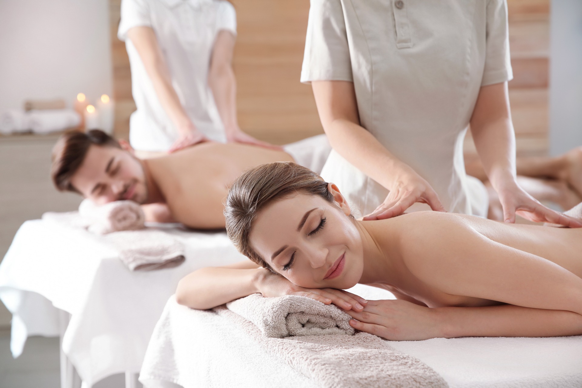 Romantic young couple enjoying back massage in spa salon 1920x1280 sp Topless young woman covering her breasts by hands