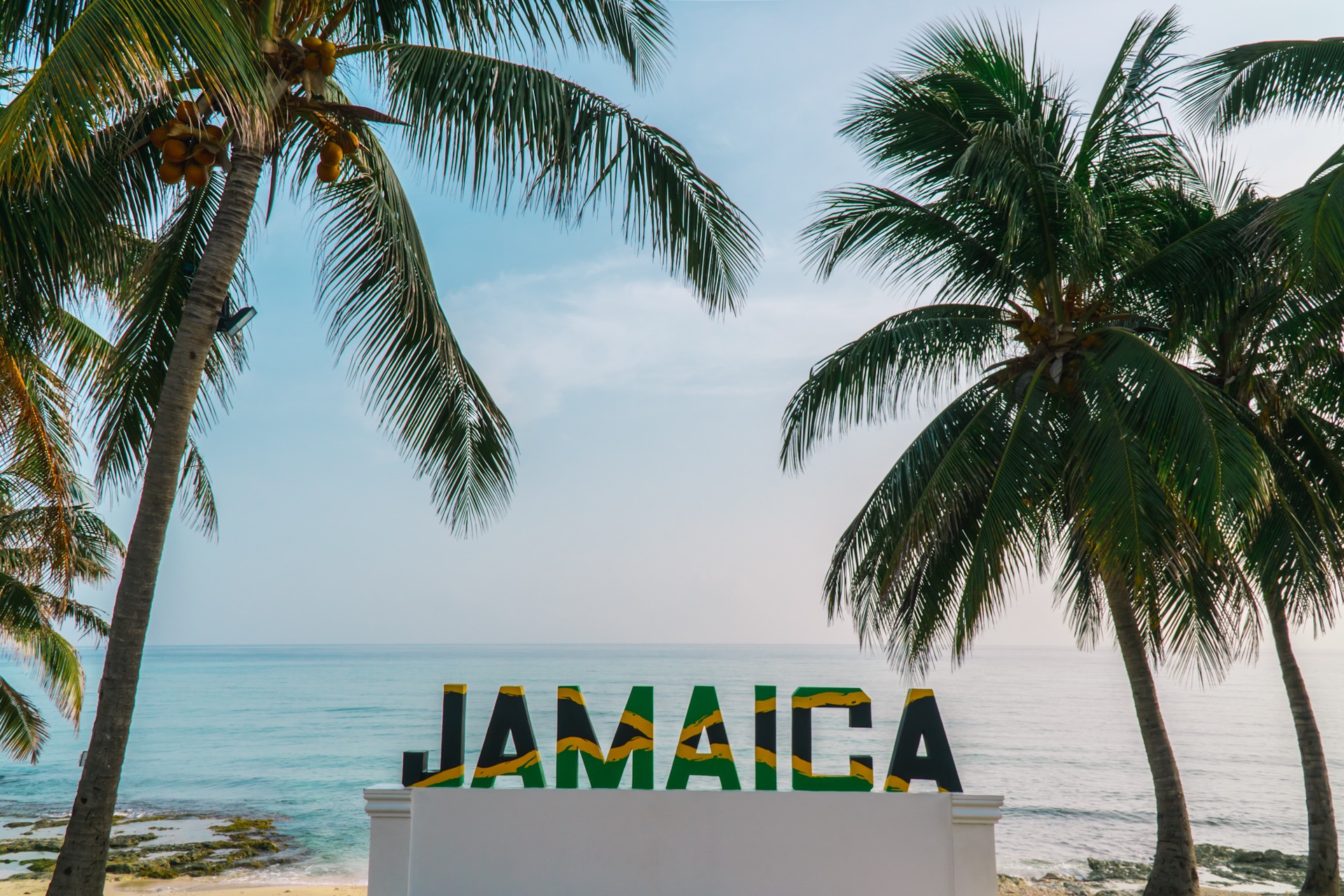 Jamaica sign. Jamaican flag with palm trees. Tropical palm tree Topless young woman covering her breasts by hands