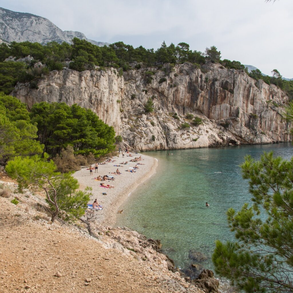 Nugal Beach – FKK-Strand Makarska, Kroatien FKK-Strand Nugal bei Makarska in Kroatien – naturbelassene Bucht mit Kiesstrand, türkisblauem Wasser und beeindruckender Steilküste, umgeben von Pinien.