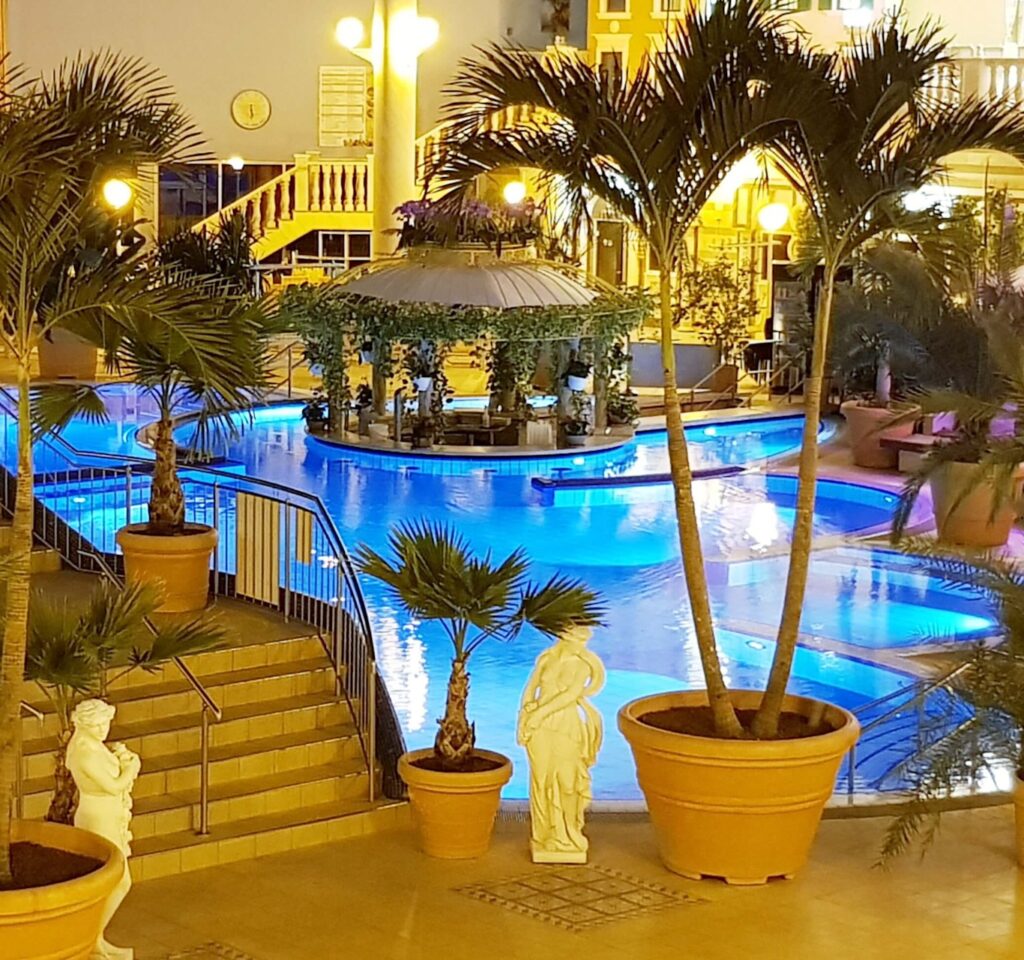 FKK-Resort Desire Riviera Maya mit Palmen, Gartenwegen und Strohdach-Pavillons in der Sonne.