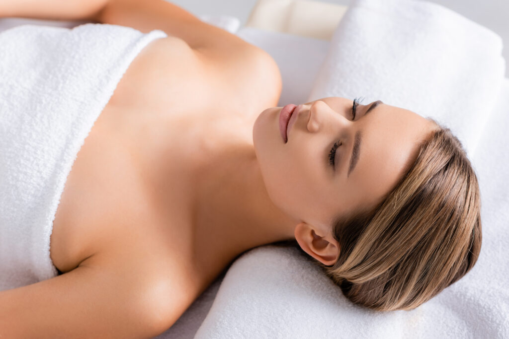 peaceful woman with closed eyes lying on massage table in spa sa FKK&Wellness FKK-Lifestyle