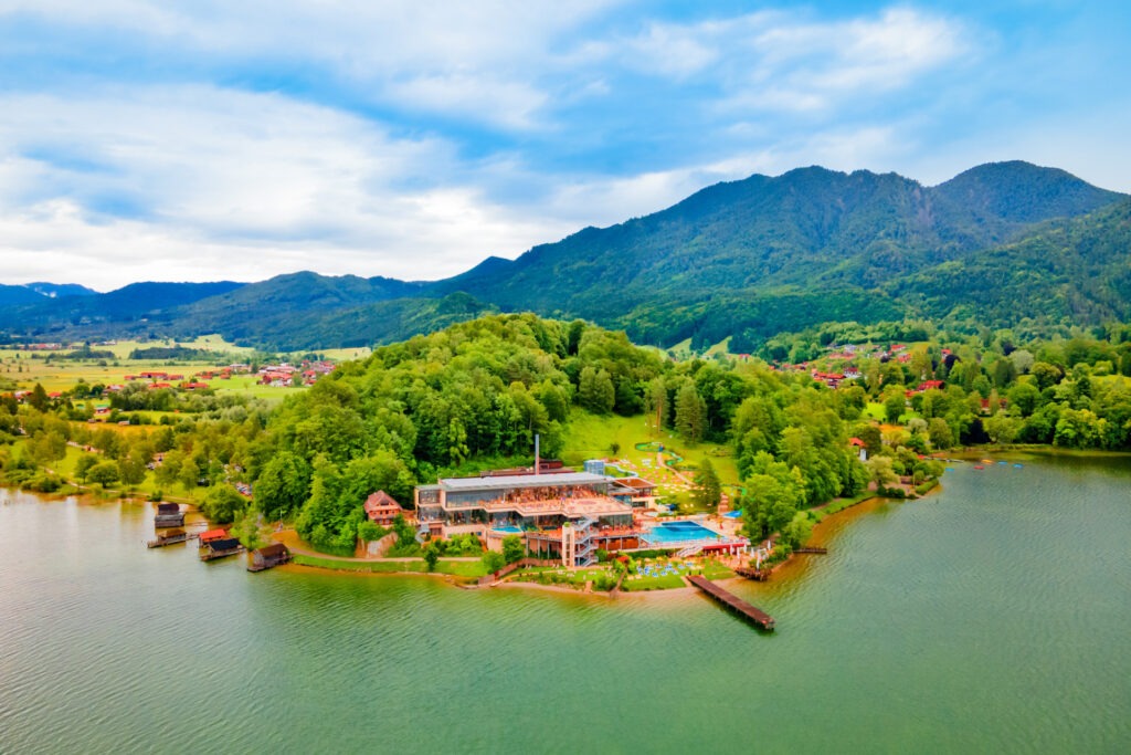 Zwei lächelnde Frauen liegen entspannt auf Handtüchern in einer Holzsauna im Warmbad Villach.