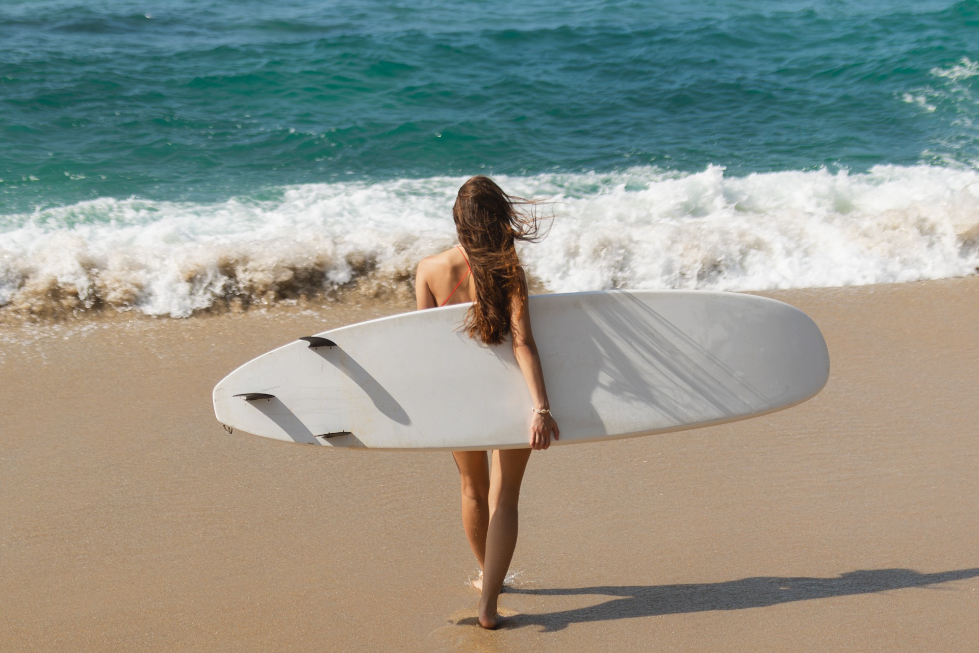 Walking Surfer Woman with Surfboard on the Tropical Beach fkk girl View of Cala Comte beach with sunbeds and umbrellas on shore, Ibiza