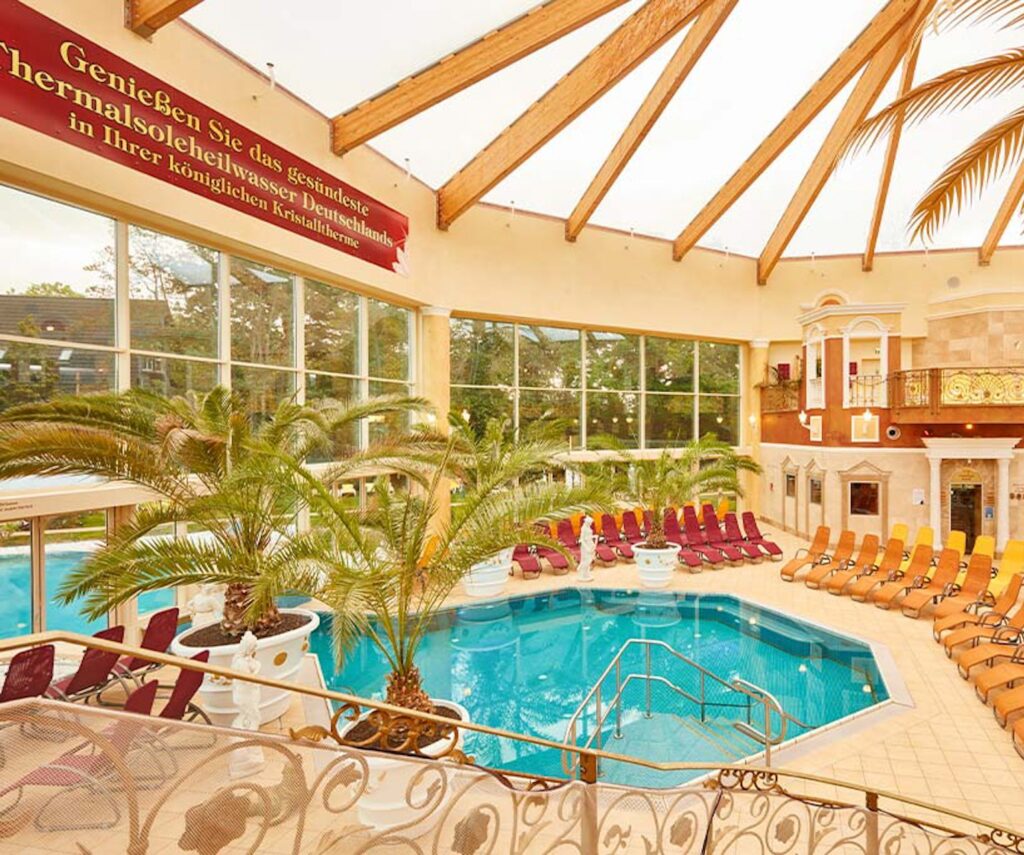 FKK-Resort Desire Riviera Maya mit Palmen, Gartenwegen und Strohdach-Pavillons in der Sonne.