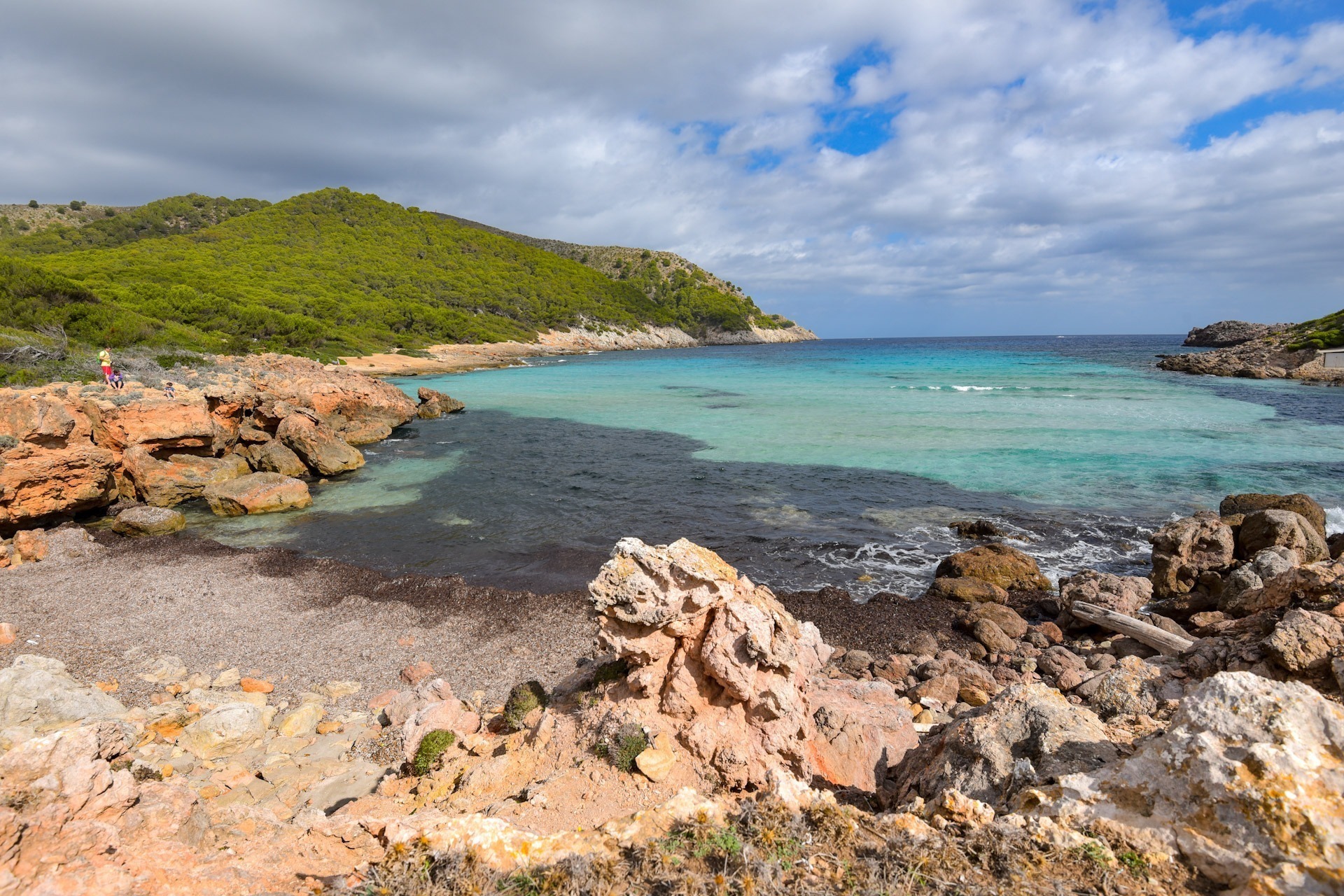 FKK-Bucht Cala M0lto auf Mallorca – naturbelassene kleine Bucht mit türkisblauem Wasser, Felsen und grüner Hügellandschaft.