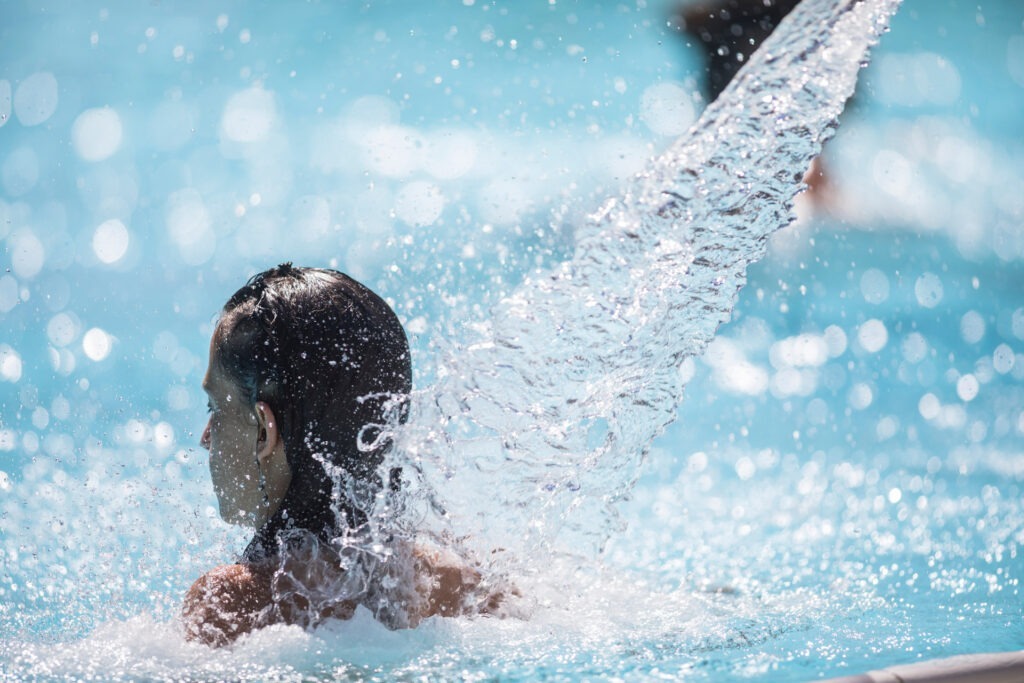 Entspannung im Spa – FKK-Wellnesshotel Bayern mit Pool und Massagewasserfall Frau genießt den Wasserstrahl im Wellnesspool eines FKK-Hotels in Bayern