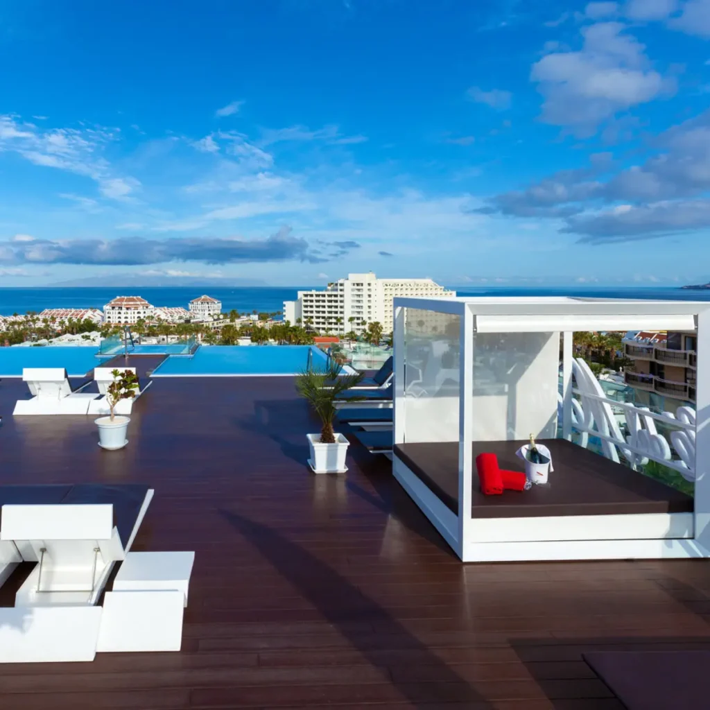 Zwei lächelnde Frauen liegen entspannt auf Handtüchern in einer Holzsauna im Warmbad Villach.