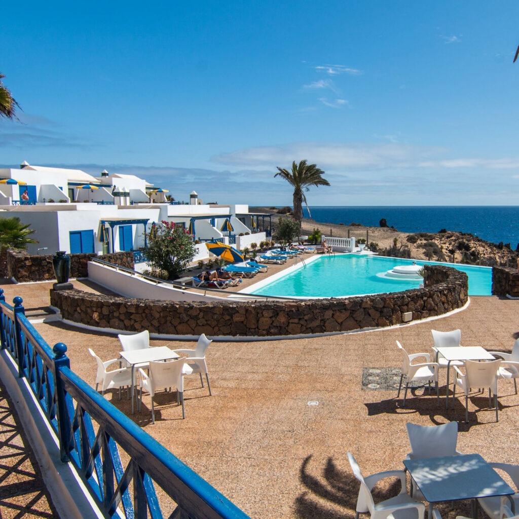 FKK-Resort Desire Riviera Maya mit Palmen, Gartenwegen und Strohdach-Pavillons in der Sonne.