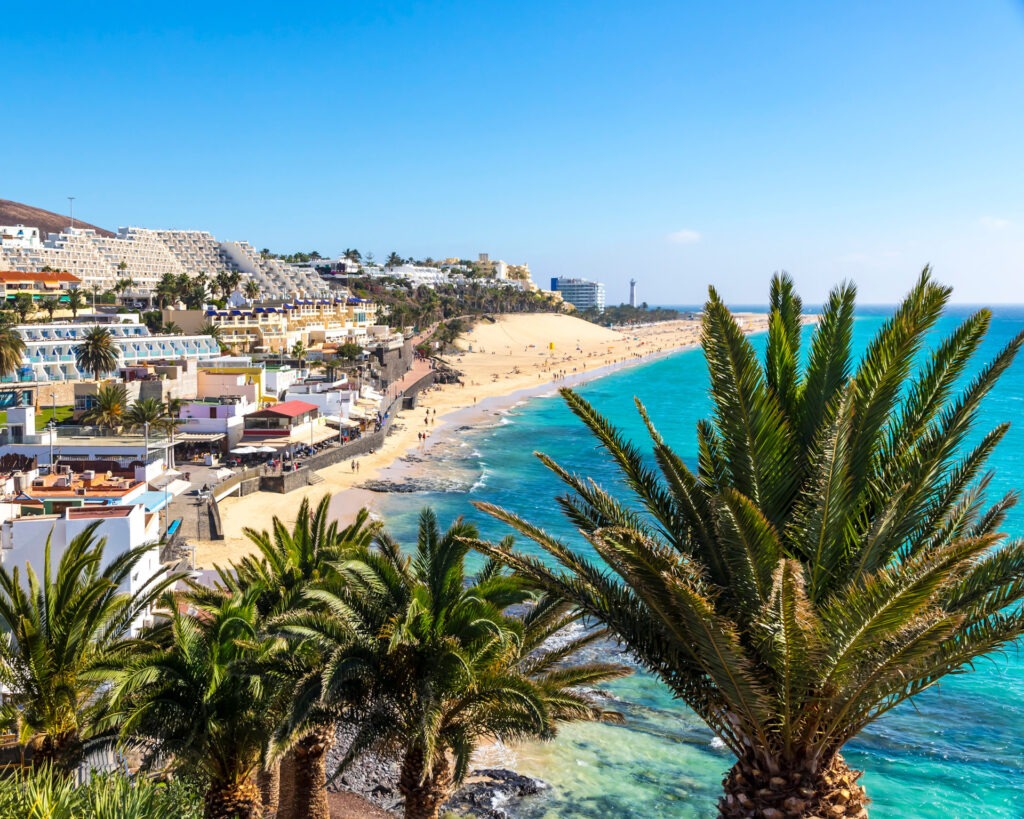 FKK-Resort Desire Riviera Maya mit Palmen, Gartenwegen und Strohdach-Pavillons in der Sonne.