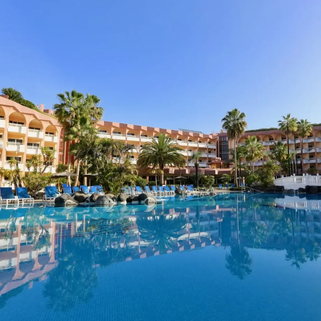 Zwei lächelnde Frauen liegen entspannt auf Handtüchern in einer Holzsauna im Warmbad Villach.