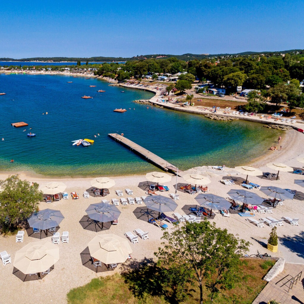 Zwei lächelnde Frauen liegen entspannt auf Handtüchern in einer Holzsauna im Warmbad Villach.