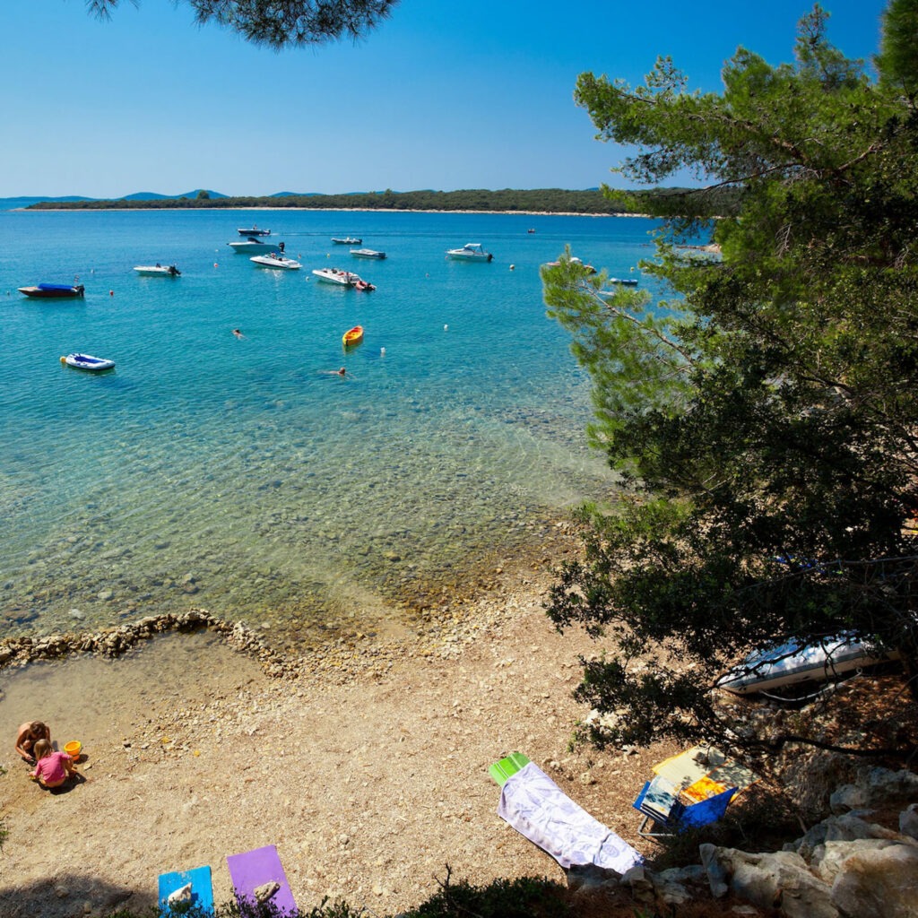 Zwei lächelnde Frauen liegen entspannt auf Handtüchern in einer Holzsauna im Warmbad Villach.