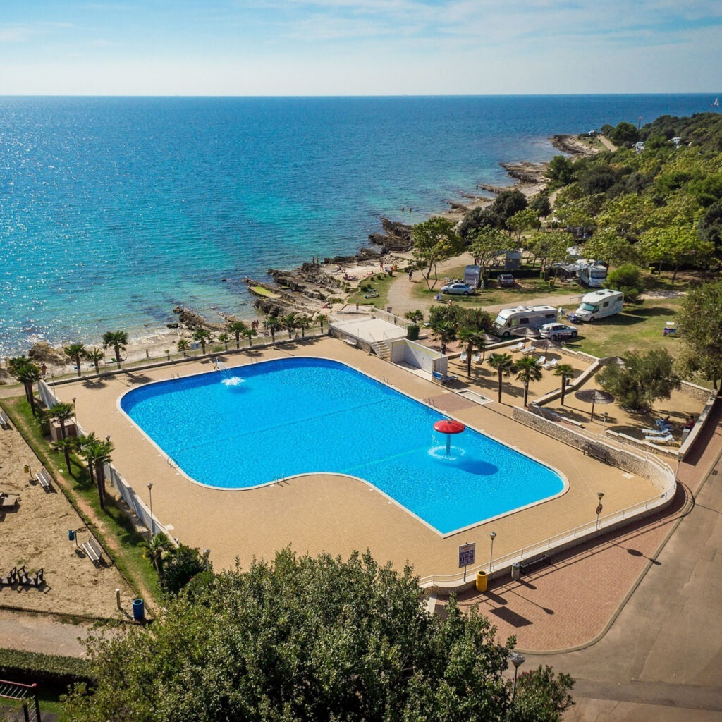 Zwei lächelnde Frauen liegen entspannt auf Handtüchern in einer Holzsauna im Warmbad Villach.