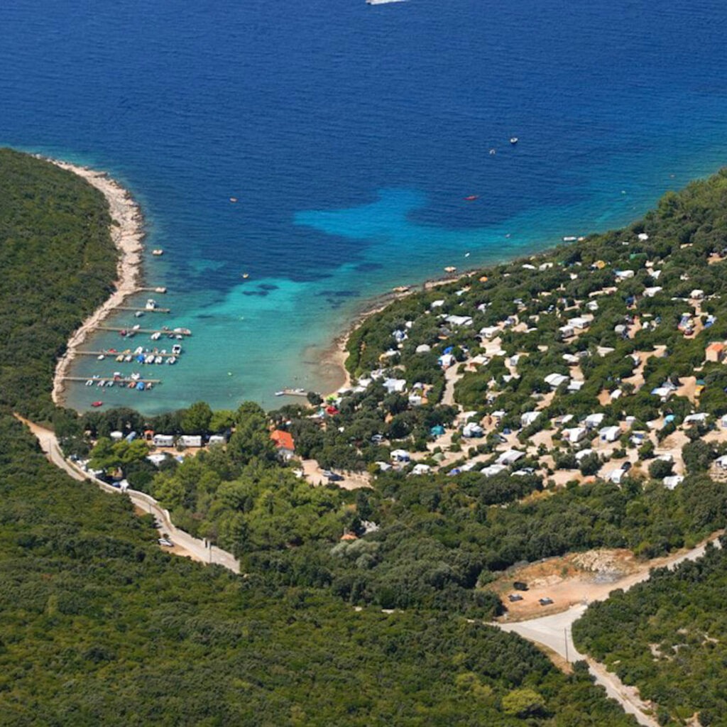 Zwei lächelnde Frauen liegen entspannt auf Handtüchern in einer Holzsauna im Warmbad Villach.