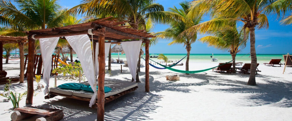 Junge Frau genießt nackt die Sonne am weißen Sandstrand eines tropischen Meeres – FKK-Urlaub, Freiheit und Entspannung pur