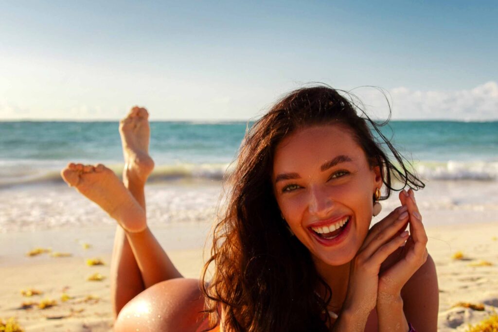 Junge Frau genießt die Sonne am FKK-Strand von Ibiza – entspannter Moment am Meer
