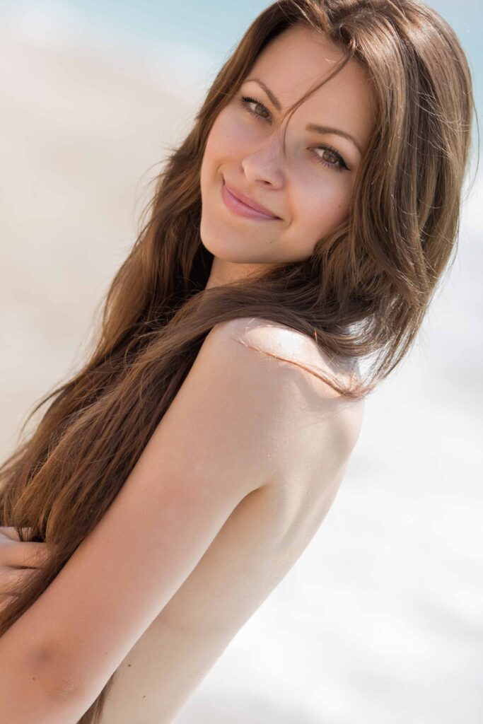 Lächelnde Frau am FKK-Strand in Spanien mit Blick zur Kamera