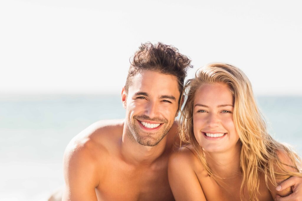 Lächelnde Frau am FKK-Strand in Spanien mit Blick zur Kamera