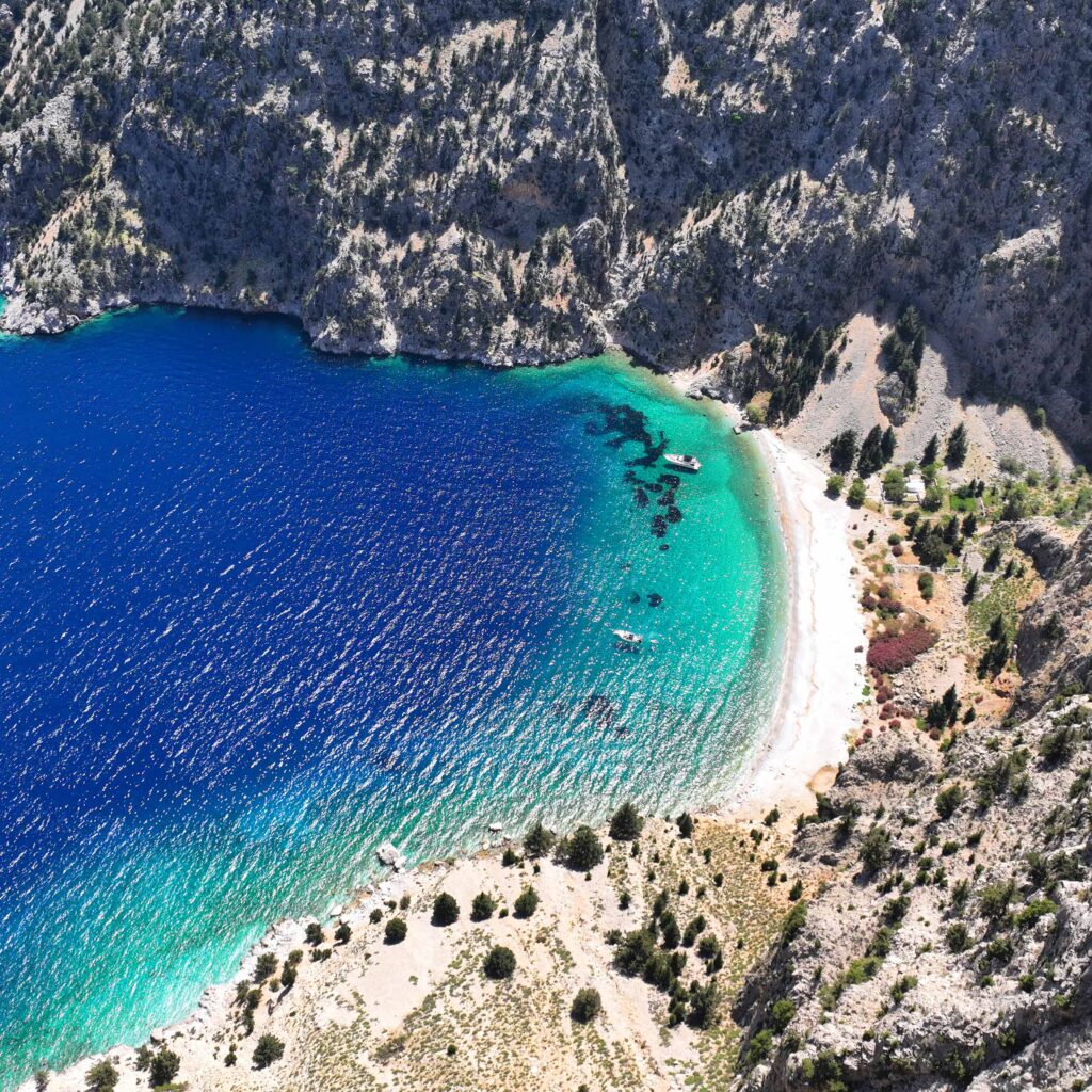 Aerial drone photo of paradise beach of Agios Georgios in island FKK-Strand Filaki Beach auf Kreta mit türkisfarbenem Wasser, Felsen und Sonnenliegen – ideal für FKK-Fans.