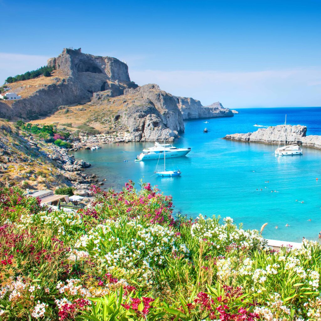 Lindos – panoramic view of St. Paul bay with acropolis of Lind FKK-Strand Filaki Beach auf Kreta mit türkisfarbenem Wasser, Felsen und Sonnenliegen – ideal für FKK-Fans.