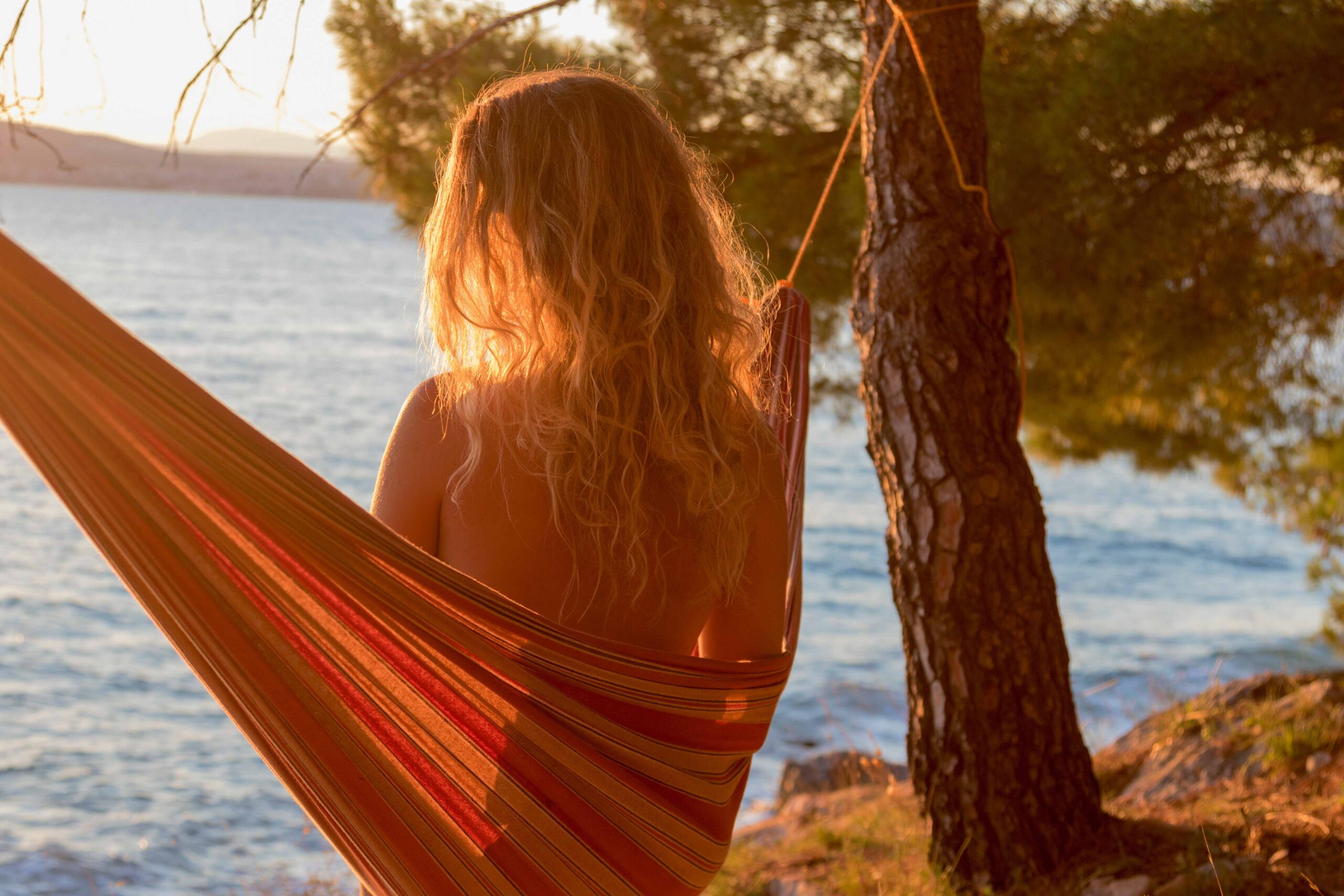 Junge Frau genießt die Sonne am FKK-Strand von Ibiza – entspannter Moment am Meer
