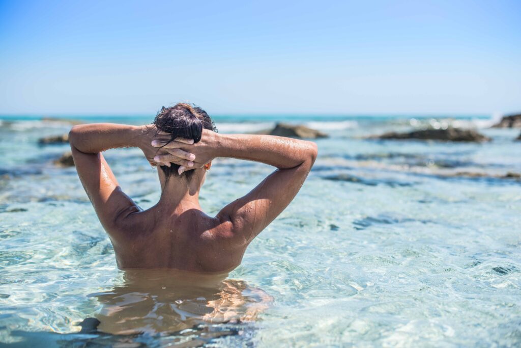 Junge Frau genießt die Sonne am FKK-Strand von Ibiza – entspannter Moment am Meer