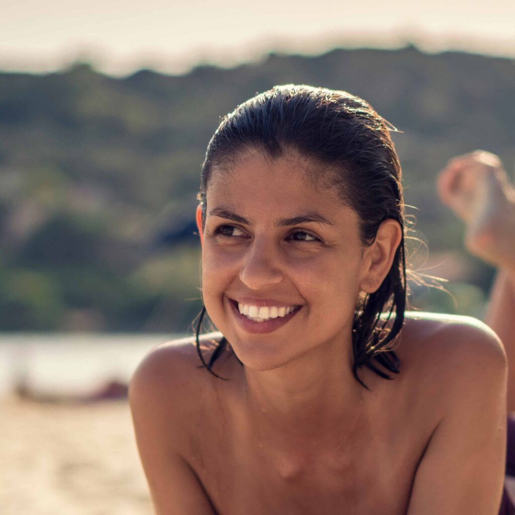 Junge Frau genießt die Sonne am FKK-Strand von Ibiza – entspannter Moment am Meer