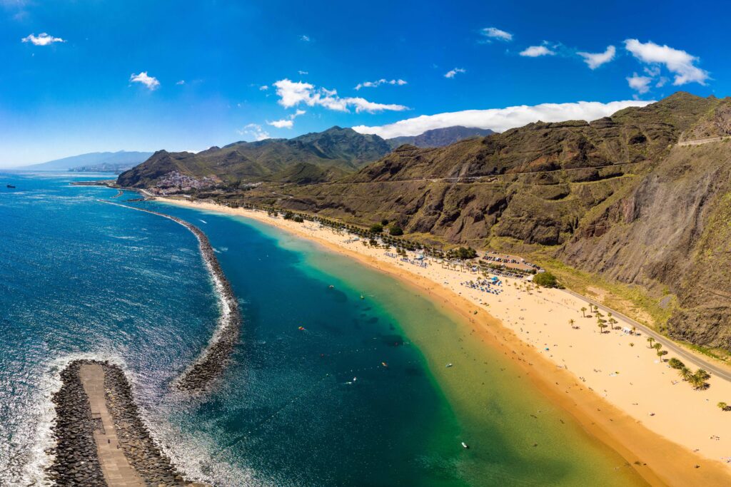Blick auf die sonnige Küste von Lanzarote mit Palmen, Blumen und Meer – perfekte Kulisse für den FKK-Urlaub im Winter.