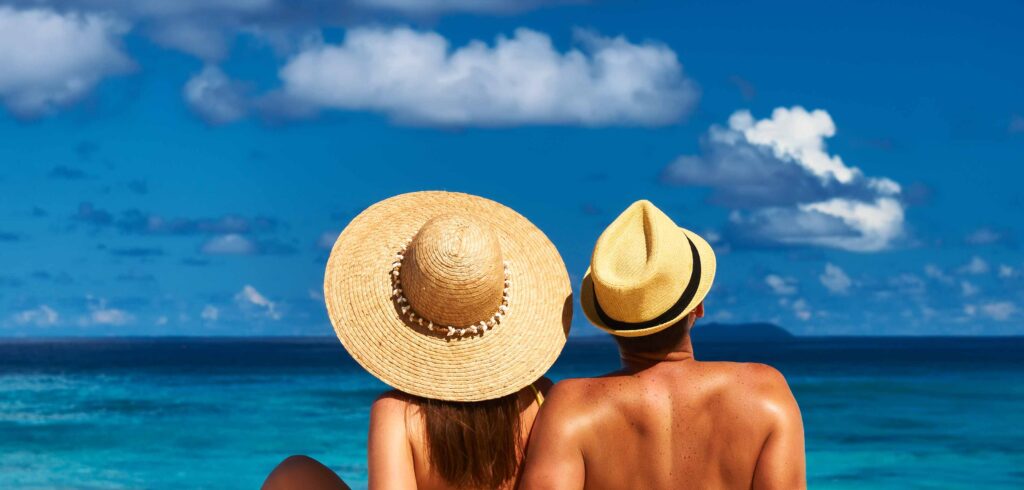 FKK Urlaub Balearen – entspannte Person sitzt im Sand am Strand und lässt Sand durch die Hände rieseln