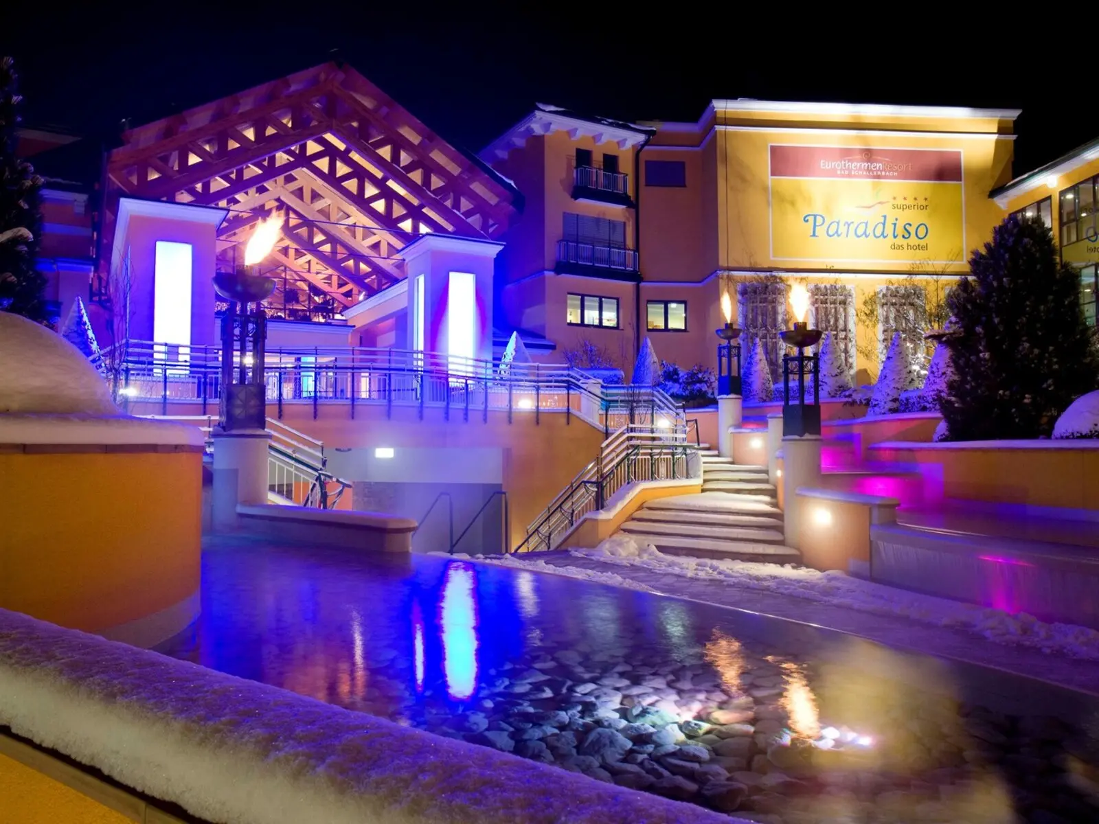 FKK-Resort Desire Riviera Maya mit Palmen, Gartenwegen und Strohdach-Pavillons in der Sonne.