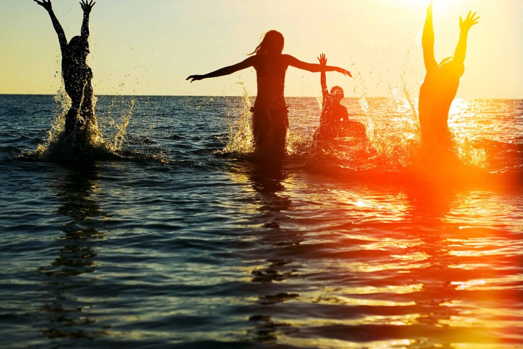 Zwei junge Frauen genießen Spaß im Meer beim FKK-Urlaub – Lebensfreude und Freiheit
