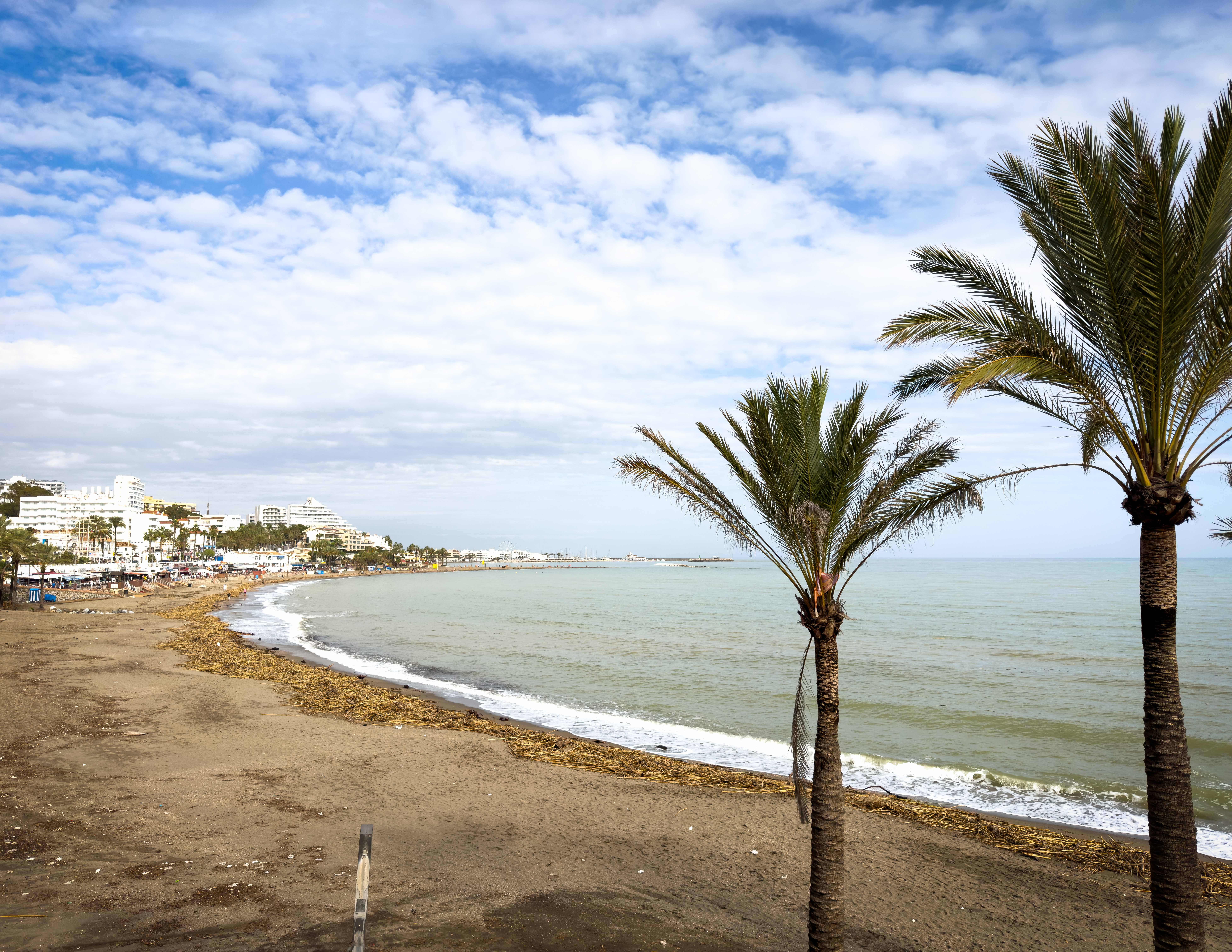 A landscape photo of Benalmádena at southern Spain's Costa del FKK-Strand Sa Canova bei Son Serra de Marina auf Mallorca – naturbelassener, langer Sandstrand mit türkisblauem Meer und Blick auf das Tramuntana-Gebirge.