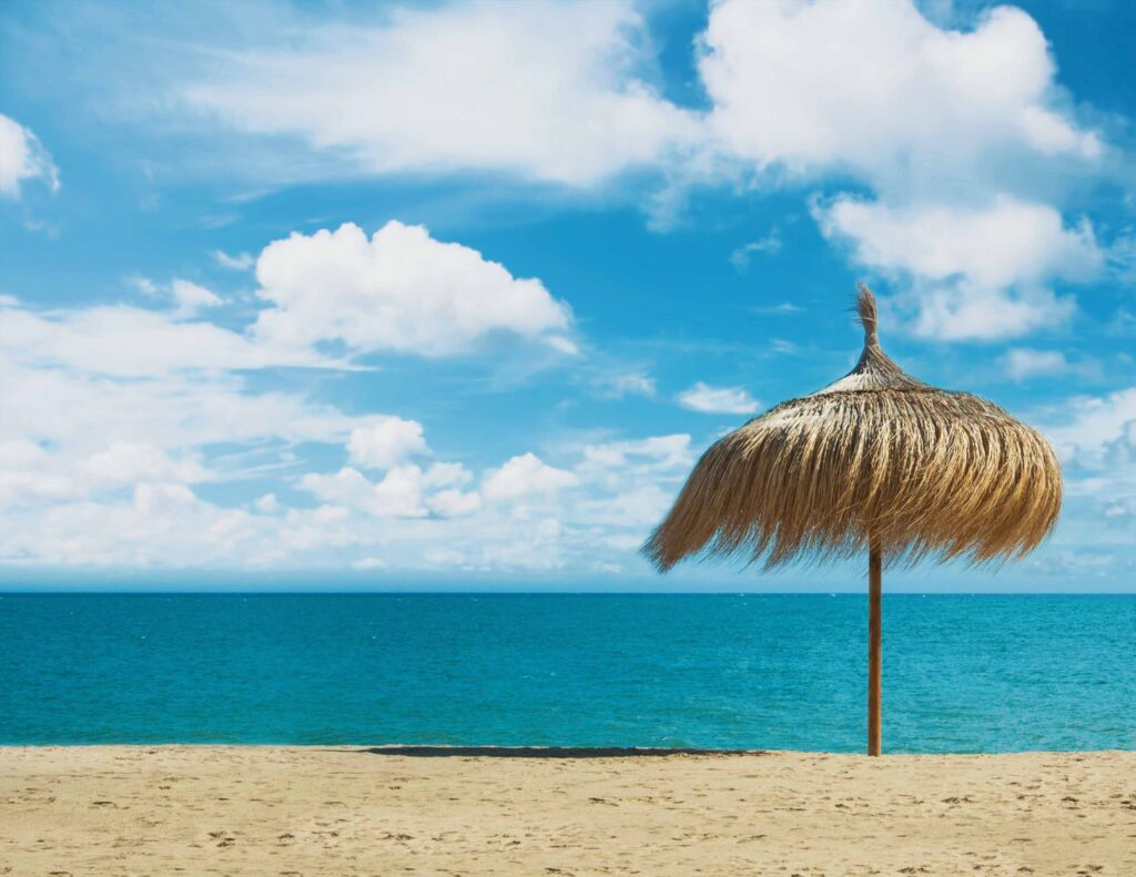 Beach umbrella made of palm leaves standing at the perfect dream Es Trenc Mallorca FKK Strand mit türkisblauem Wasser und weißem Sand
