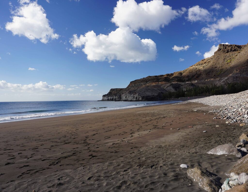 Playa Veneguera FKK-Strand Playa de Güigüi auf Gran Canaria – schwarzer Sandstrand zwischen Felsen und Atlantik, umgeben von Steilküste und wilder Natur