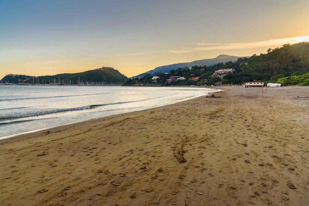 Beach on Tombolo della Feniglia in Orbetello on peninsula Argentario at sunset. Italy Luftaufnahme des Plage Naturiste de Cap d'Agde mit kilometerlangem Sandstrand, Yachthafen und Mittelmeerküste in Südfrankreich.