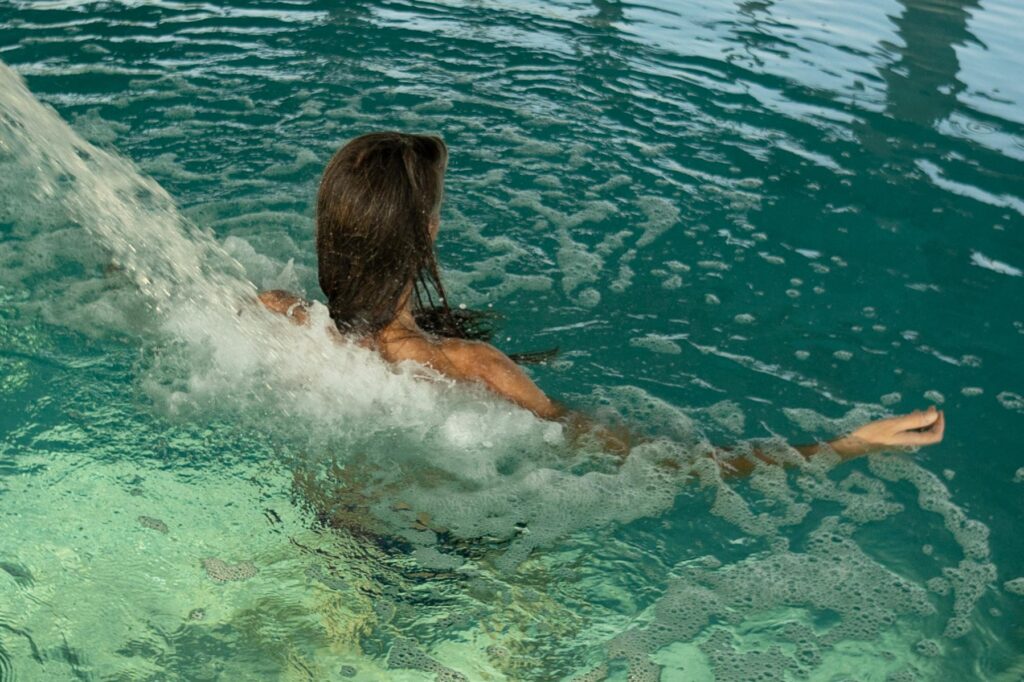 Young woman enjoying hydromassage in thermal bath at spa center Kristall Rheinpark-Therme Bad Hönningen mit Thermalbecken und Eingang zur staatlich anerkannten Heilwasser-Therme in Rheinland-Pfalz