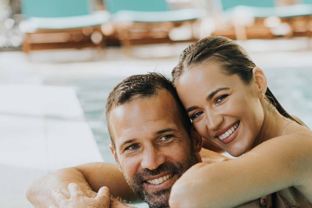 Young couple relaxing in the indoor swimming pool Kristall Trimini Therme Kochel am See – Thermalbecken und Saunalandschaft mit Berg- und Seeblick, Ort für FKK-Wellness und Entspannung in Bayern.